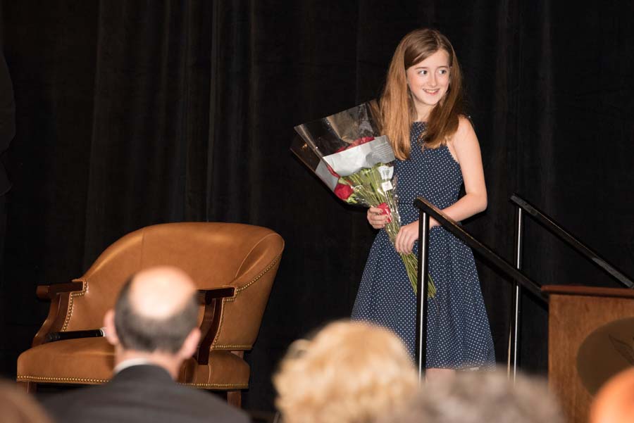 A girl on stage with a bouquet 