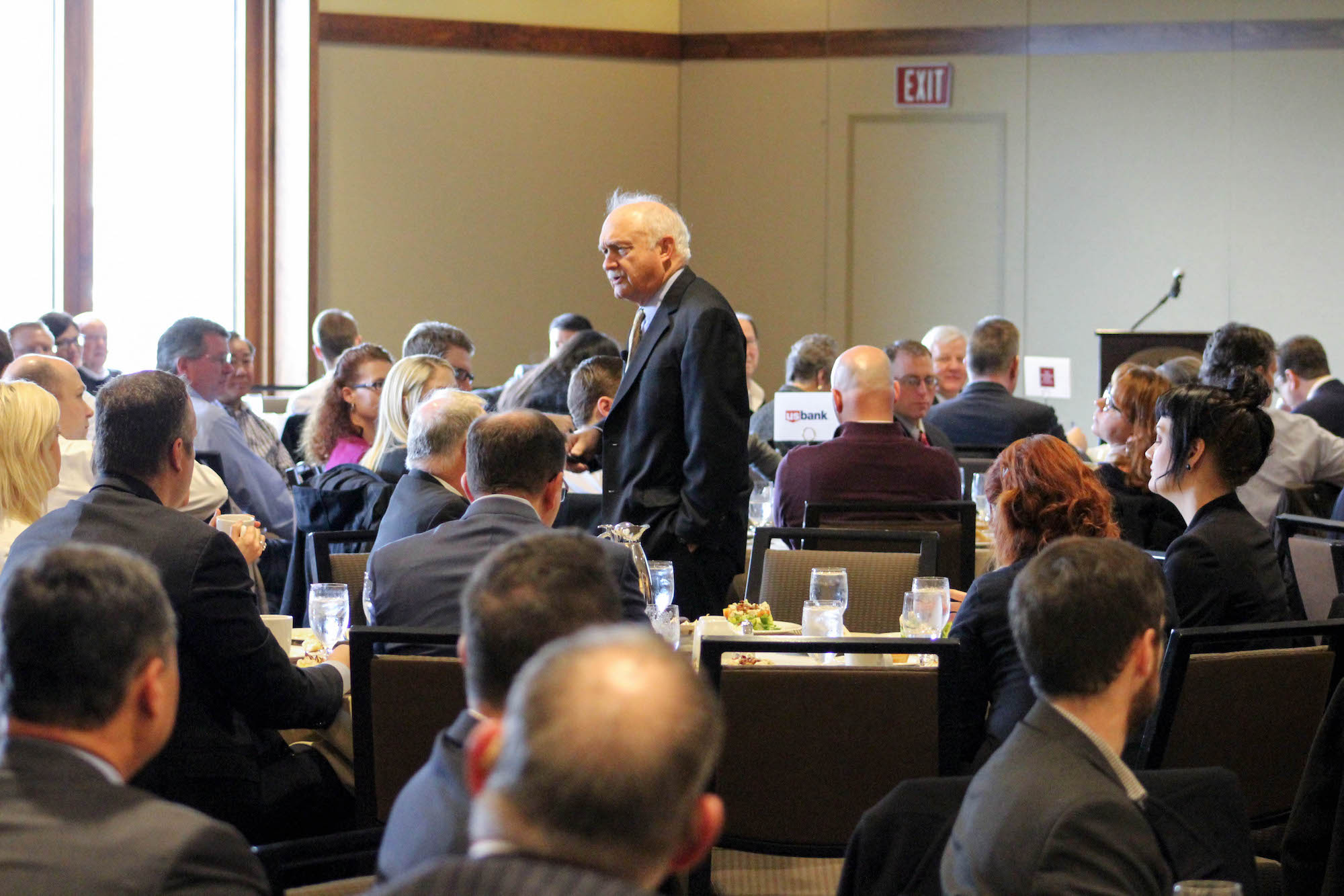 An old man presenting while standing in the middle of the room