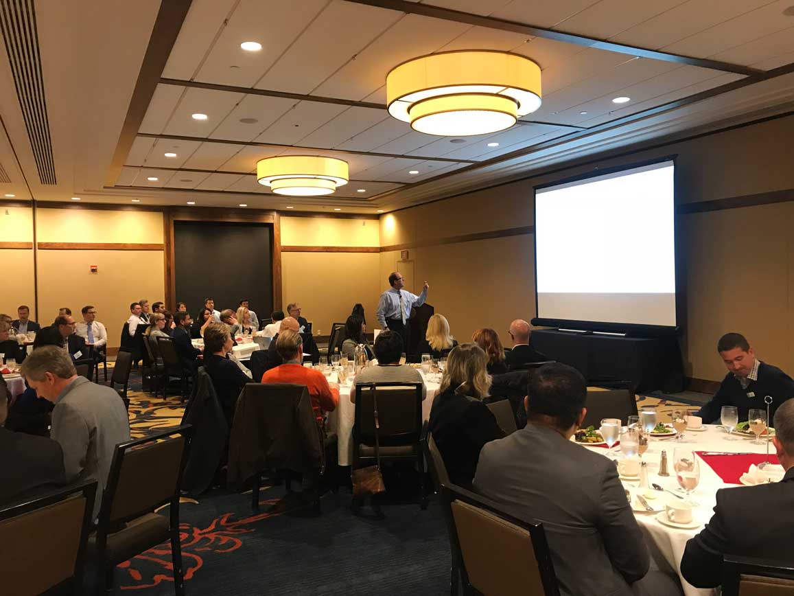 Man presenting slides to room full of people