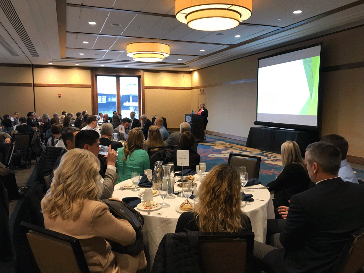 Women presenting in a fully packed conference room