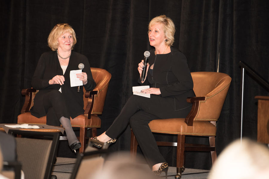 Ladies holding a mic and talking while sitting on a chair on stage