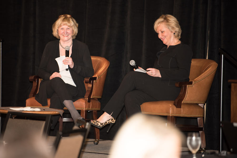 Women on stage holding mic and smiling