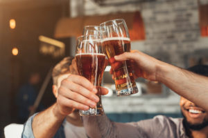 Colleagues raising their beer glasses at an after work happy hour 